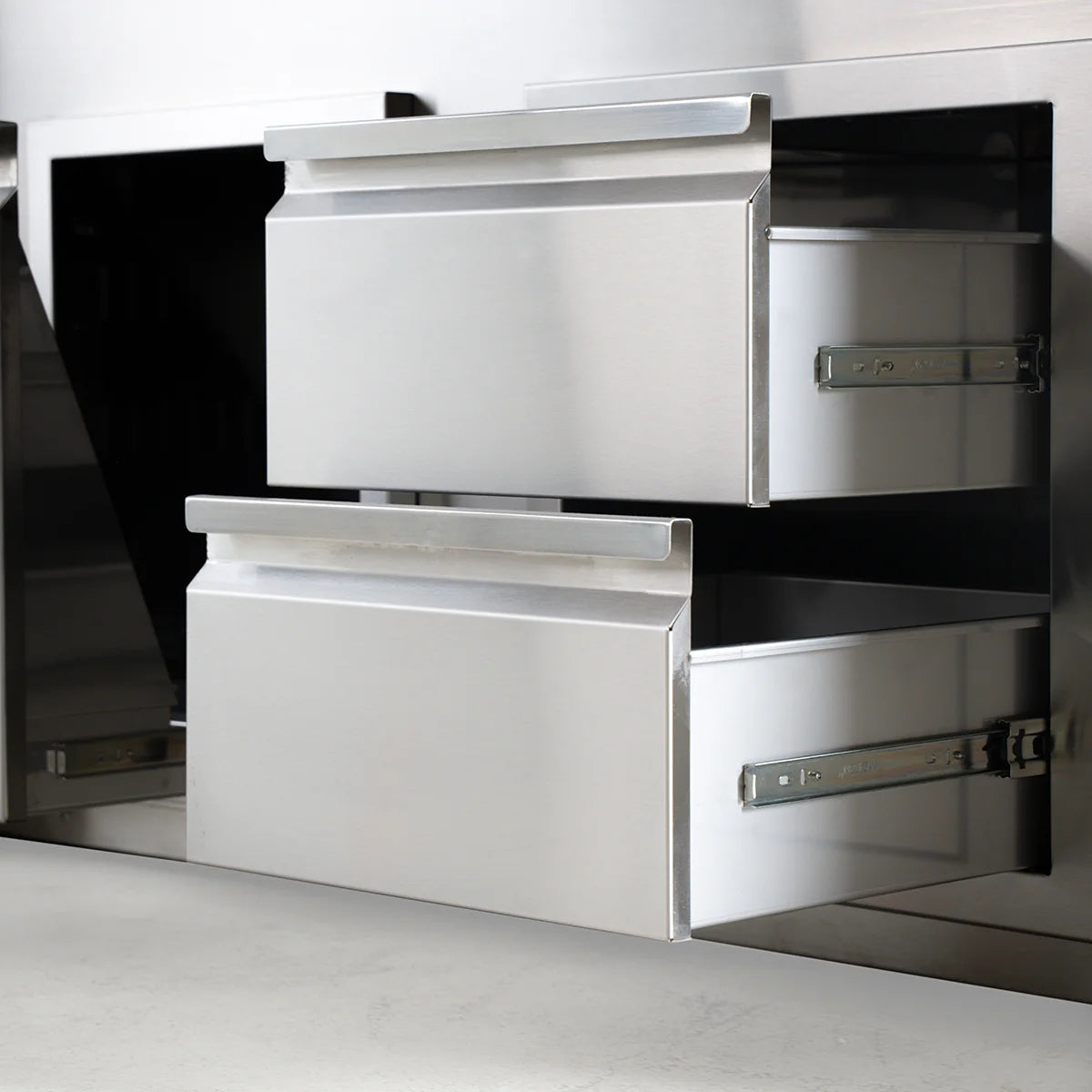 Stainless steel kitchen appliance with open drawers on a light gray background