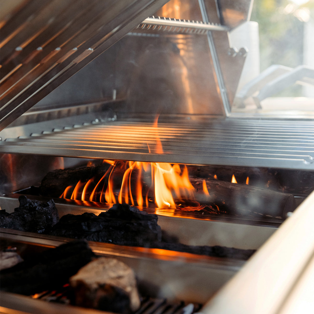 Burning wood chunks and charcoal in the American Made Grills Encore hybrid grill fuel trays